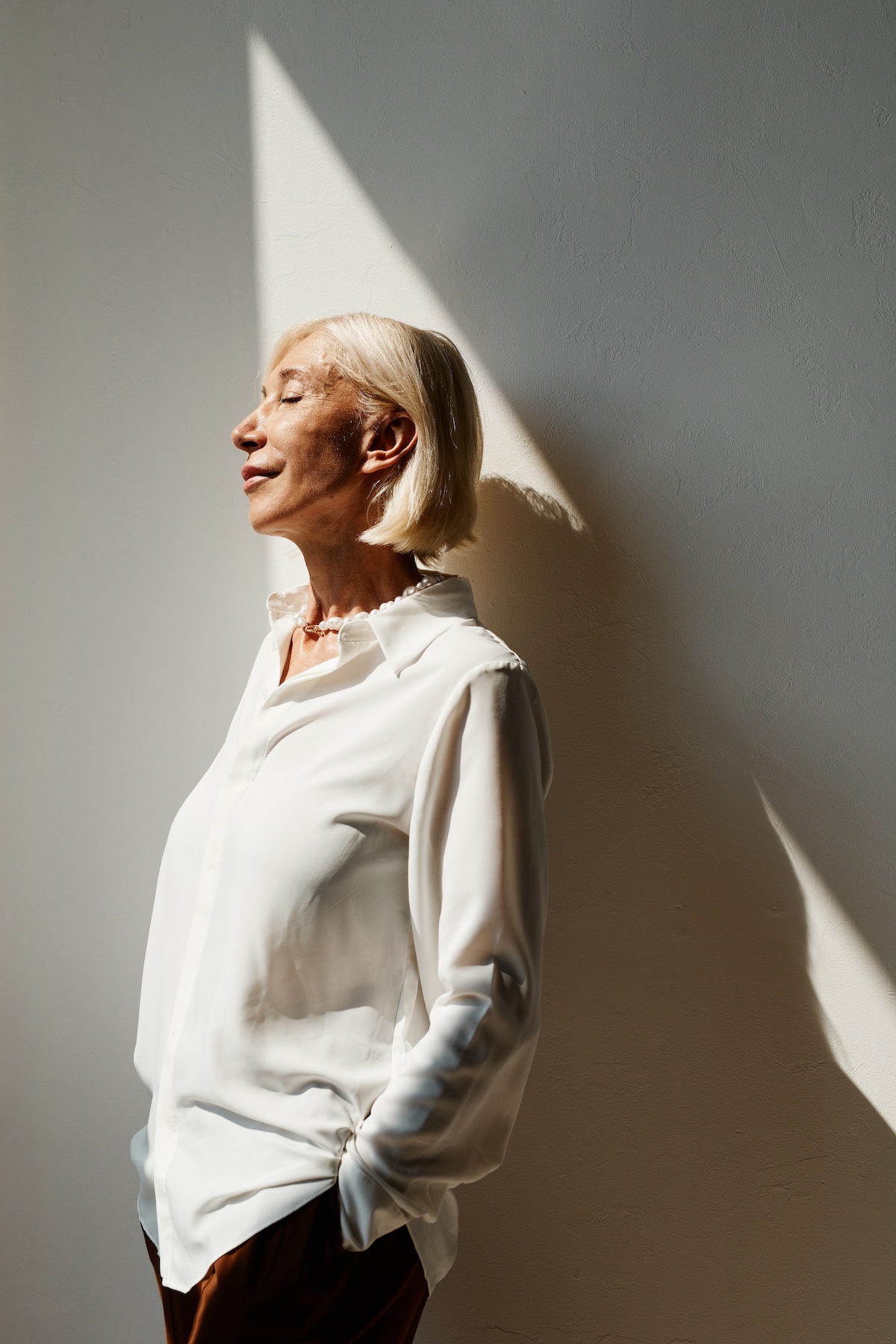 beautiful elegant mature woman standing on shadowy wall